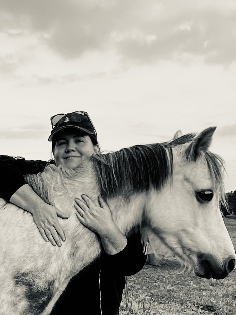 image of Kelly hugging a horse and smiling.