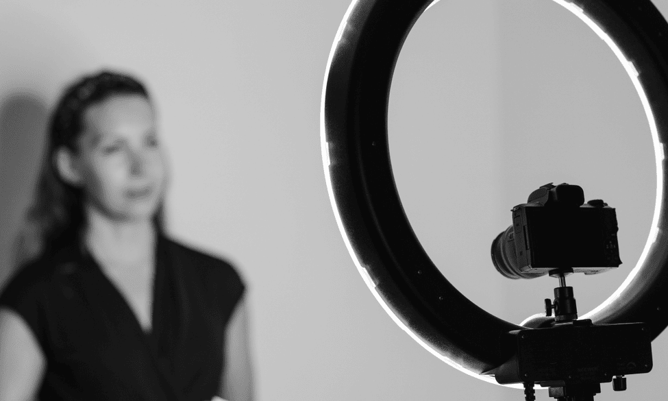 A woman looks towards a ring light and camera
